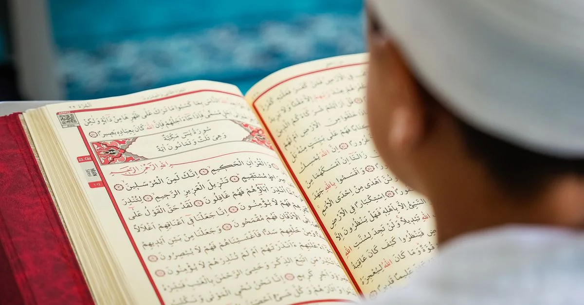Un enfant lisant attentivement des pages du Coran, s'imprégnant ainsi d'études culturelles et religieuses.