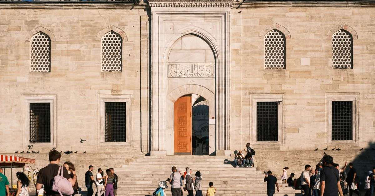 Une scène vivante de personnes marchant et socialisant en dehors d'une mosquée historique à Istanbul pendant la journée.