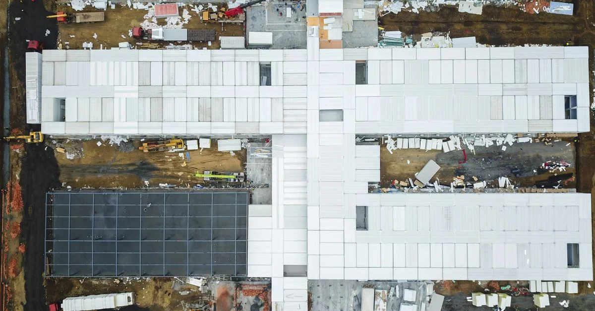 Prise de vue par drone capturant une vue aérienne d'un grand chantier avec des bâtiments inachevés.