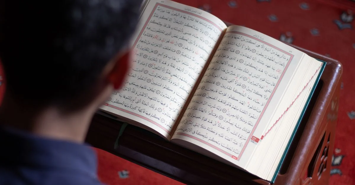 Un homme lit le Coran, soulignant la foi islamique dans une ambiance de mosquée.