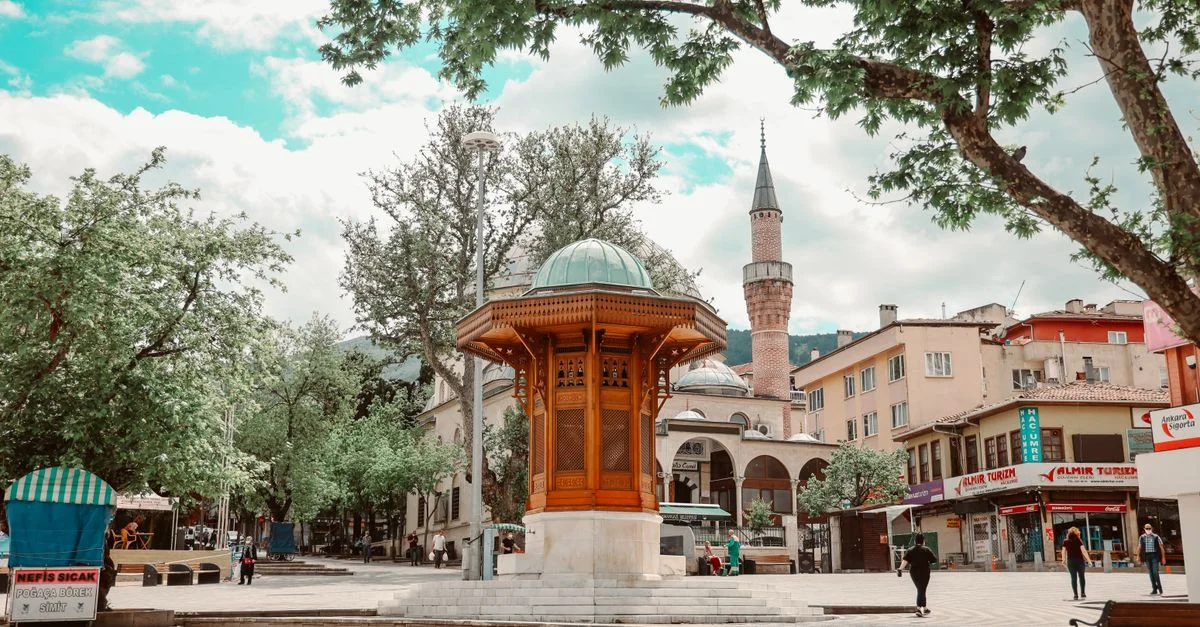Charmante place de ville avec une architecture traditionnelle et une mosquée dans un cadre urbain animé.