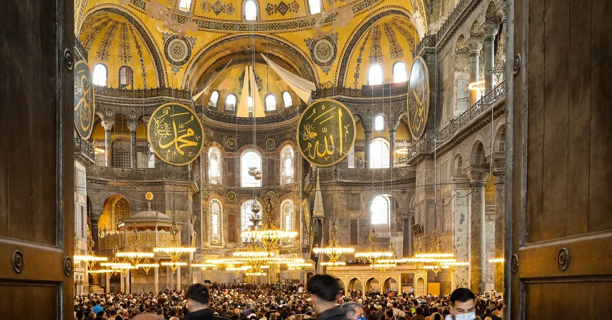 Une foule animée à l'intérieur d'une mosquée historique d'Istanbul, mettant en valeur l'architecture islamique et l'ambiance spirituelle.